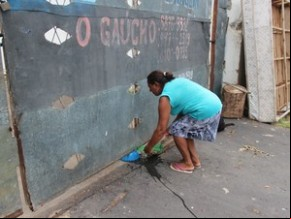 Dona Alzenira alimenta os animais pela brecha em baixo do portão.(Imagem:Gustavo Almeida/G1)