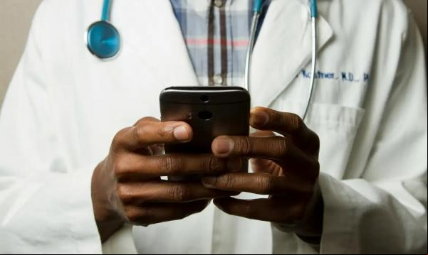 Médico com estetoscópio fala no celular.(Imagem:National Cancer Institute/Unsplash)